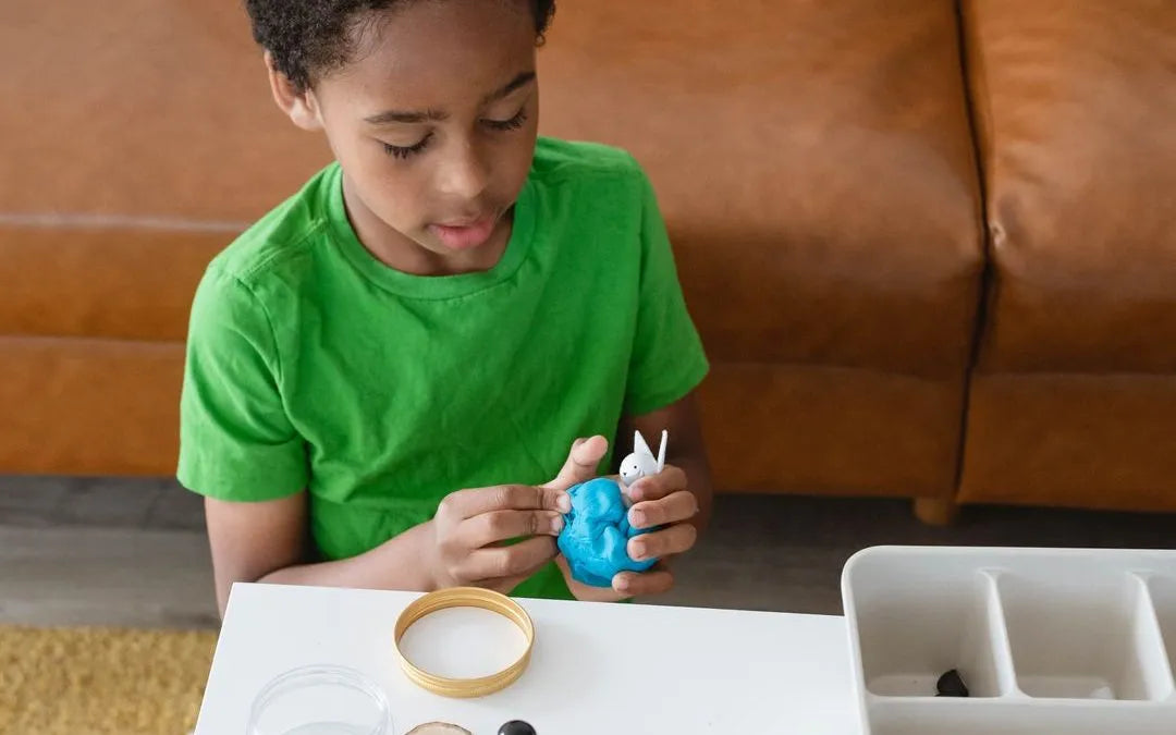 Child playing with Meemzy Magic Arctic Adventures sensory kit. Holding wooden arctic fox and blue dough.