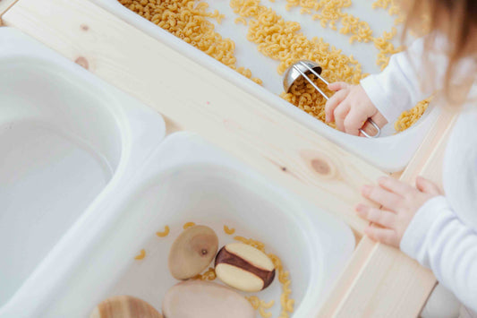 child playing in sensory bin with metal spoon