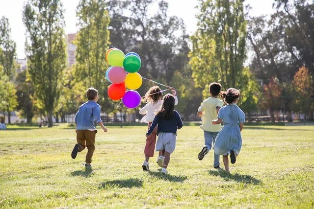 children running outside with balloons.