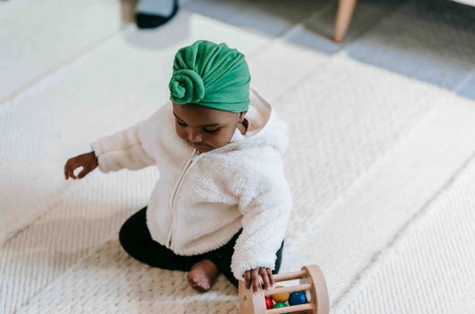 baby in a green hat playing with a toy