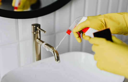 person's hands in yellow gloves cleaning a sink