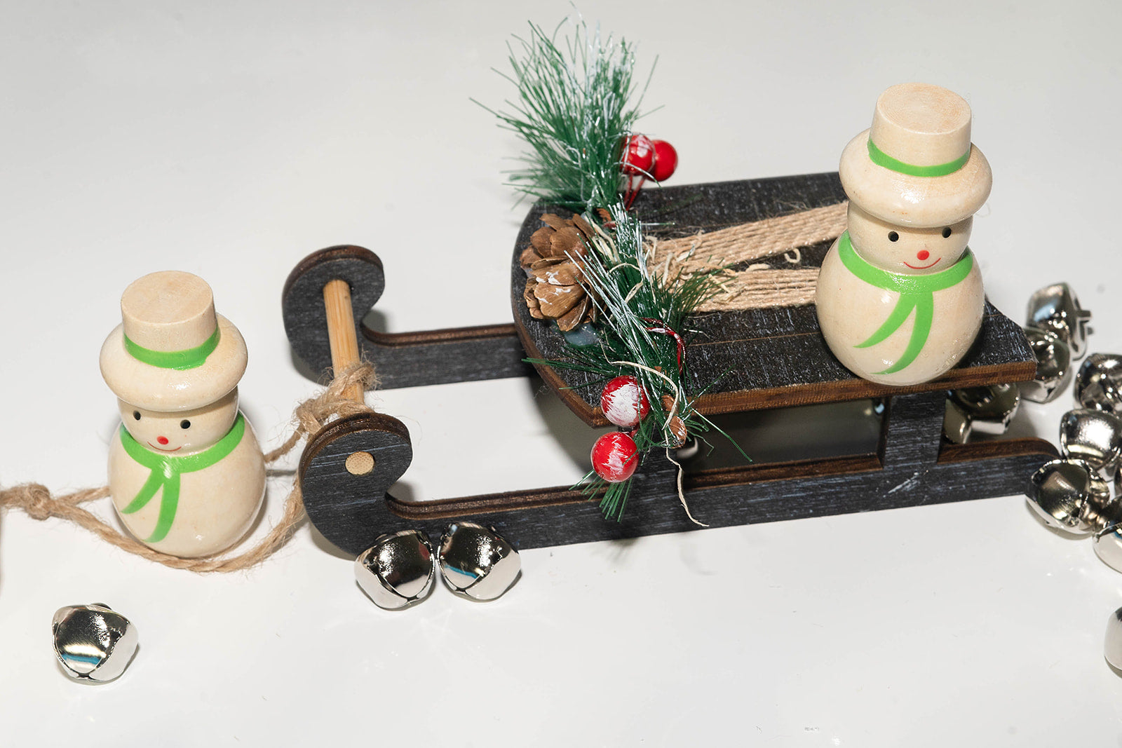 Beige wooden snowman in top hat and scarf playing on festive wooden sled.