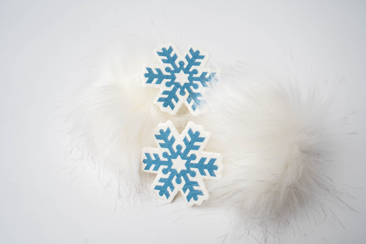 blue snowflake shaped, plantable seed paper, sat beside two faux fur balls.