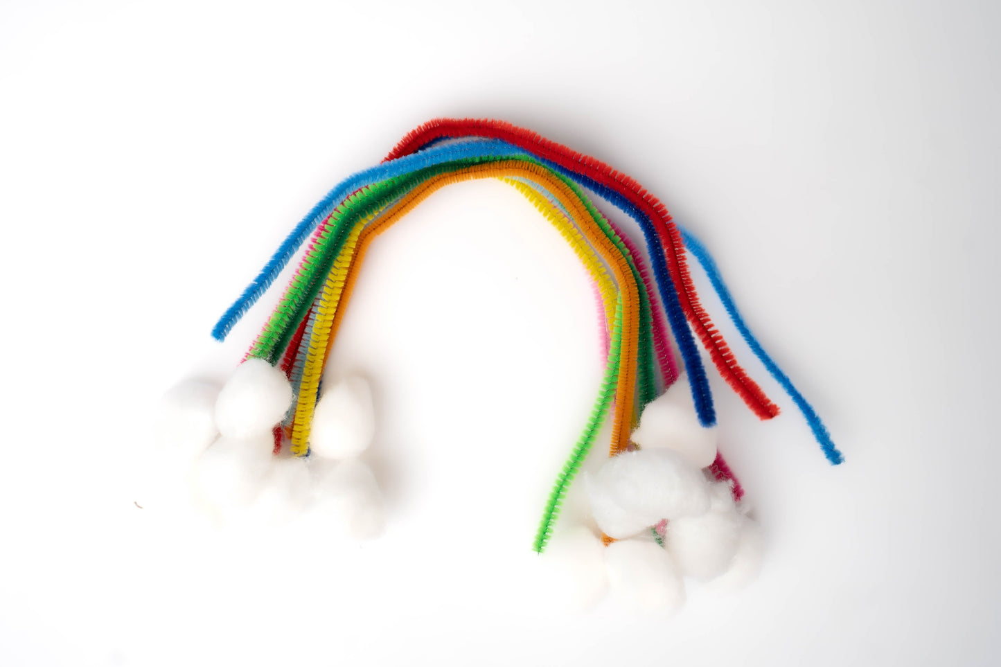 Rainbow pipe cleaners and white cotton balls shaped into a rainbow with clouds
