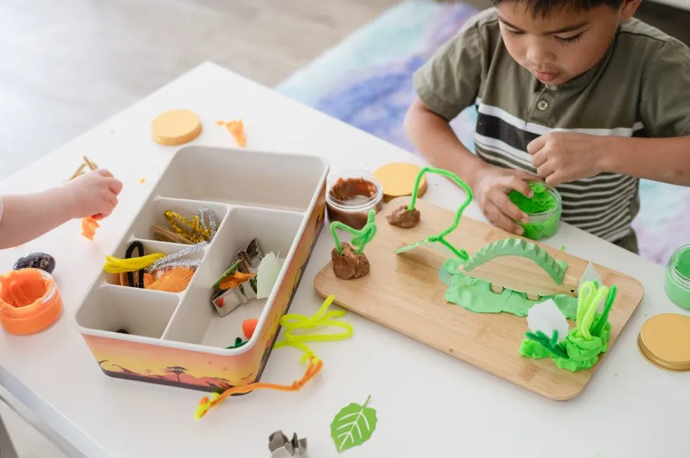 child playing with meemzy magic dinosaur sensory bin toy with play dough and wooden dinosaurs.