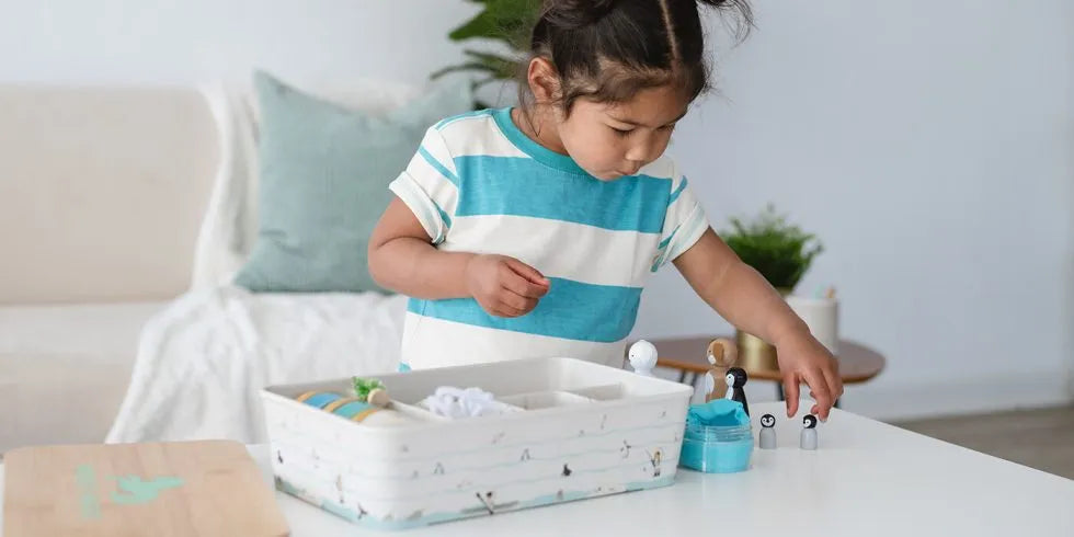 child playing with meemzy magic arctic adventures sensory kit with play dough and wooden arctic fox and penguins.