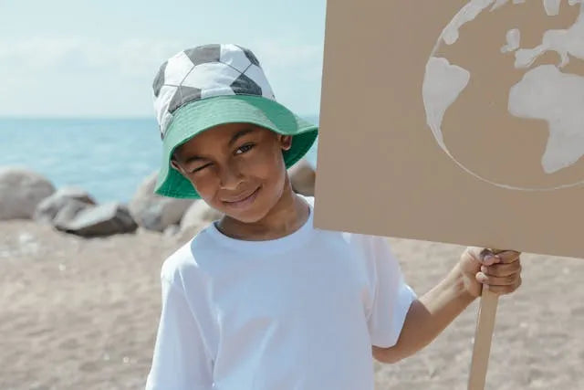 child on the beach holding a sign for earth day