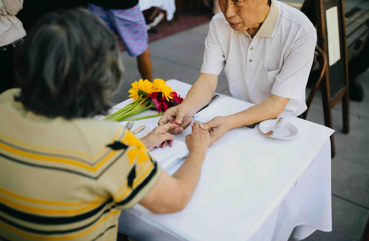 an older man and women holding hands over a table