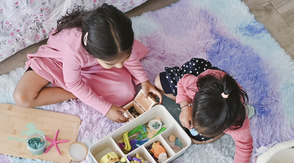 children playing with Meemzy Magic Mermaids Explore Under the Seas sensory kit with play dough, sea shells, starfish, and a treasure chest.