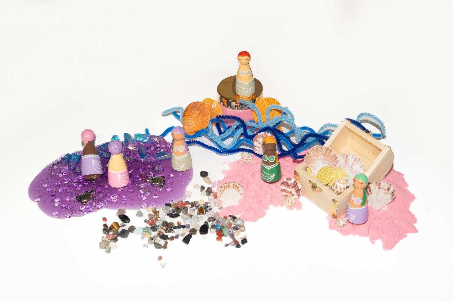 Mermaid kit contents include: purple slime, pink kinetic sand, wooden treasure chest, wildflower seed paper treasure coins, real sea shells, rainbow colors stones, shades of blue pipe cleaners, and wooden peg doll mermaids hand painted
