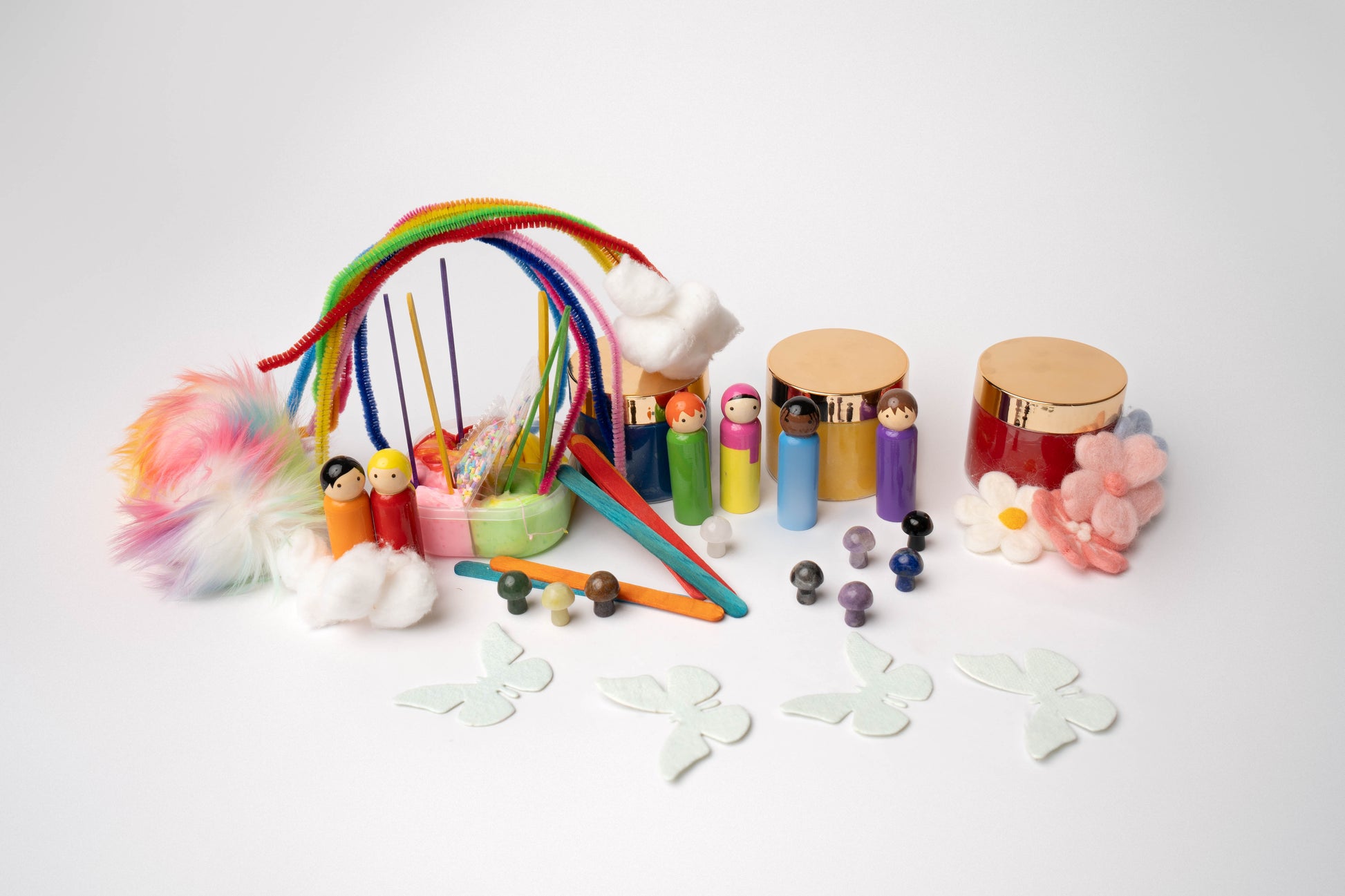 Contents include: rainbow pipe cleaners, rainbow colors peg doll people (6), rainbow slime, red, yellow, and blue dough, felt flowers (pink, white, purple), rainbow colored popsicle sticks, colorful crystal mushrooms, rainbow tipped white faux fur poofs, and pale blue seed paper butterflies