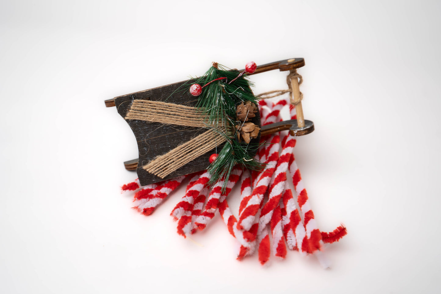 Wooden Christmas sleigh with red and white peppermint pipe cleaners