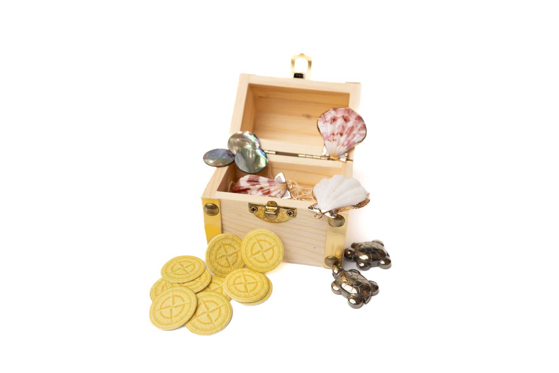 Wooden treasure chest open with contents including pyrite sea turtles, seed paper coins, sea shells lined with gold, and abalone coines